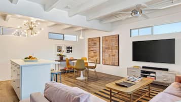 Un espacio de estar moderno con comedor, sofá, mesa de centro y televisor.