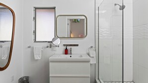 A modern bathroom with a white vanity, a mirror, a shower, and a window. - The Rosalie by AvantStay (Palm Springs)