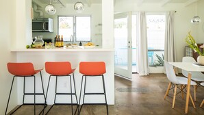 A modern kitchen with a central island, bar stools, and a dining area with a white table and chairs. - The Wesley by AvantStay (Palm Springs)