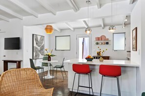 Une cuisine moderne dotée d’un îlot central, de tabourets de bar et de luminaires suspendus.