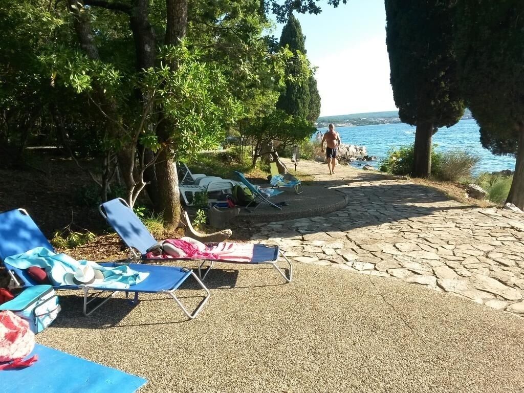 A beachside area with lounge chairs, a stone pathway, and a view of the sea.