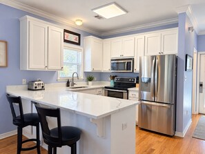 A kitchen with white cabinets, a stainless steel refrigerator, a microwave, and a toaster. - Good Day Sunshine - 4BR/3BA Old Florida Village Home - Sleeps 8 - Community Pool (Santa Rosa Beach)