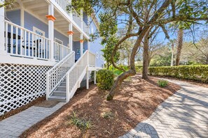A residential property with a covered porch, a staircase, and a landscaped garden with trees and shrubs. - Good Day Sunshine - 4BR/3BA Old Florida Village Home - Sleeps 8 - Community Pool (Santa Rosa Beach)