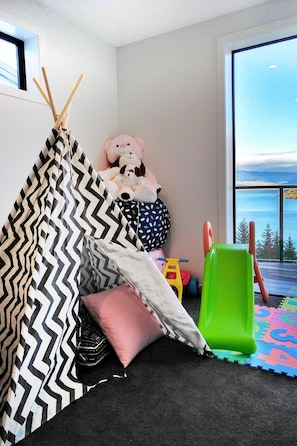 Um quarto acolhedor com uma tenda listrada em preto e branco, uma janela grande com vista para o oceano e uma cadeira verde.