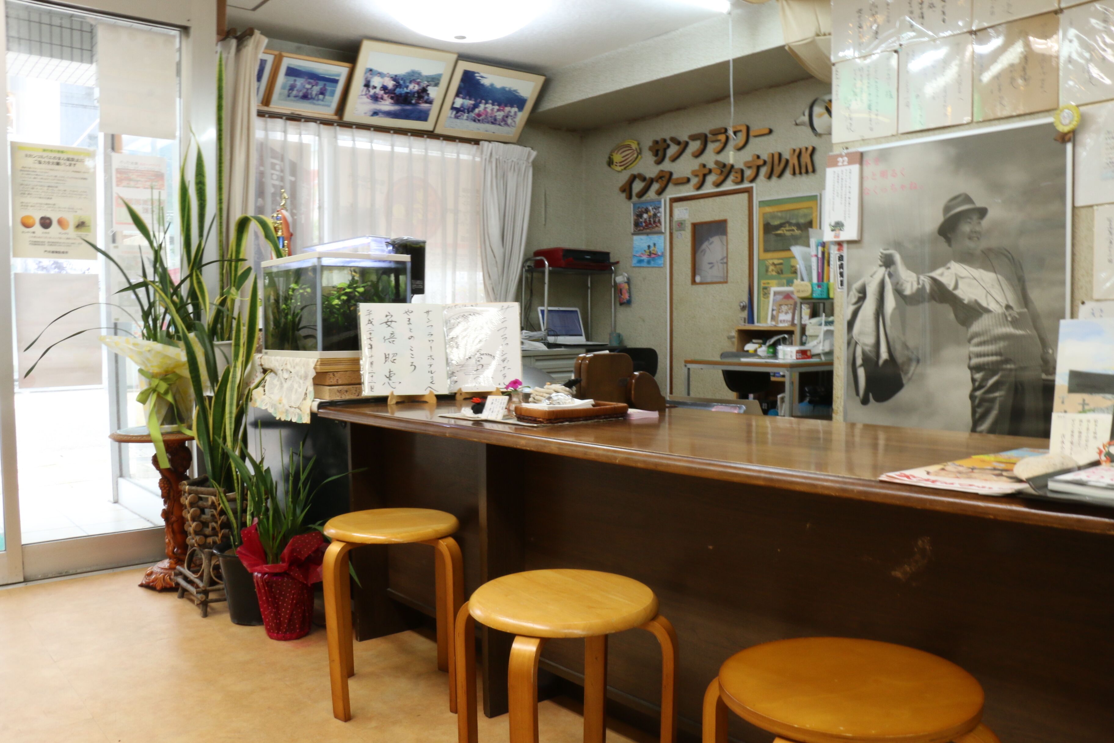 A reception area with wooden stools, a reception desk, a computer, and a large poster on the wall.