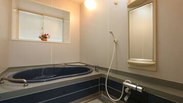 A modern bathroom with a freestanding bathtub, a window with a flower vase, and a wall-mounted mirror.