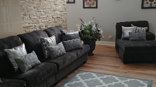 A living room with a sectional sofa, a smaller sofa, a patterned rug, and a potted plant. - Spacious home 28 miles from Downtown Chicago (Hammond)