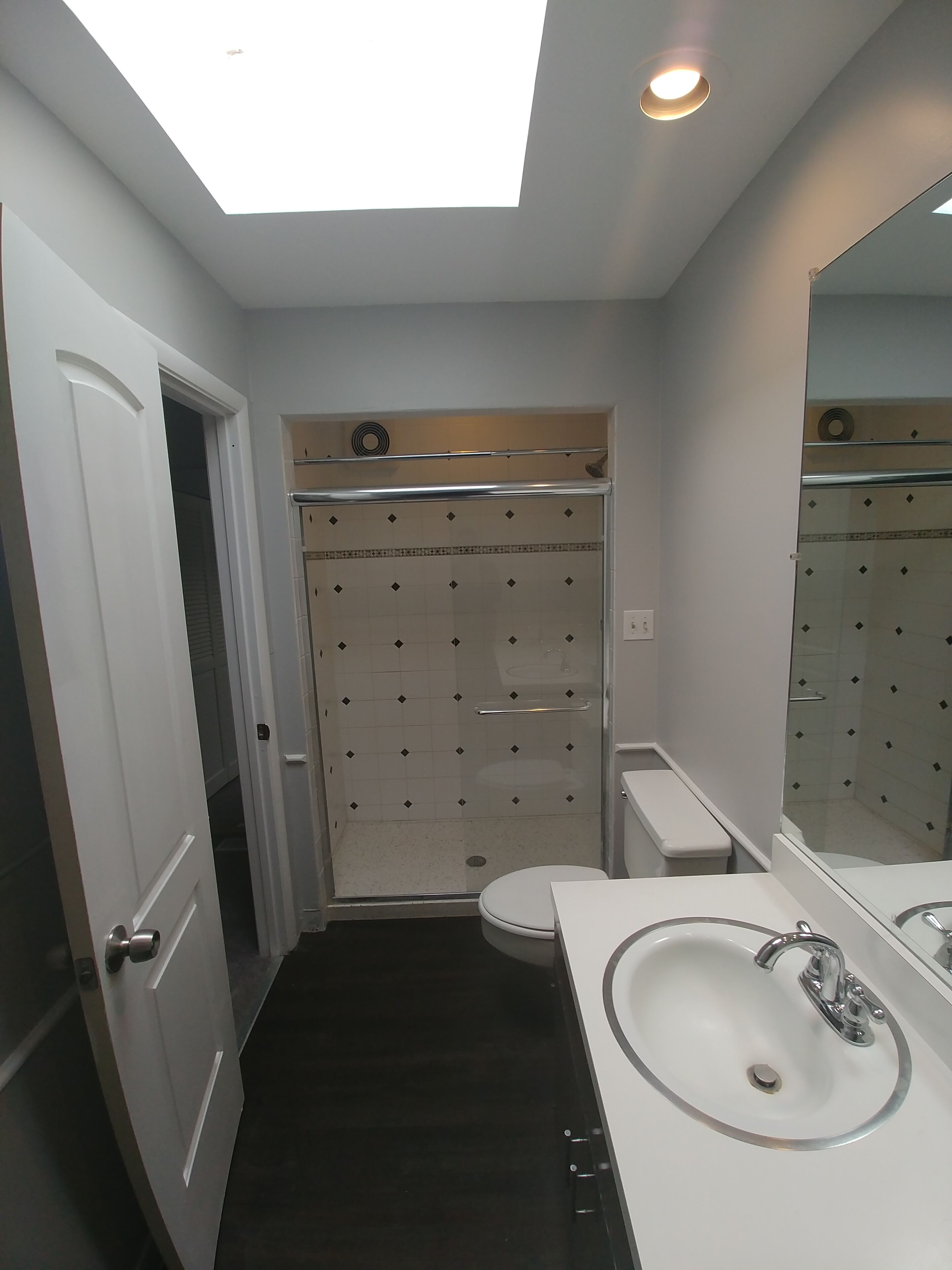 Un baño moderno con tragaluz, cabina de ducha, inodoro y lavamanos.