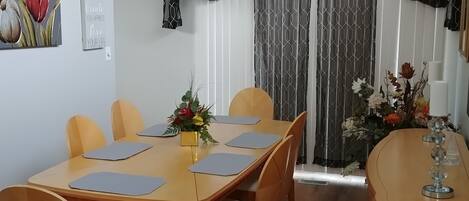 A dining area with a wooden table, chairs, and a vase with flowers.