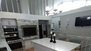 A modern kitchen with a central island, built-in appliances, and a flat-screen TV. - Spacious home 28 miles from Downtown Chicago (Hammond)