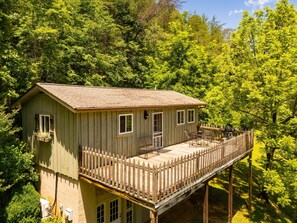 A wooden cabin with a deck, surrounded by dense green foliage. - Romantic Mountain Cottage Near Boone (Purlear)