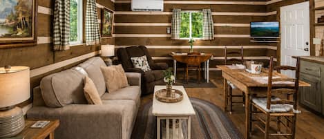 A cozy living room with a sofa, a dining table, and a ceiling fan.