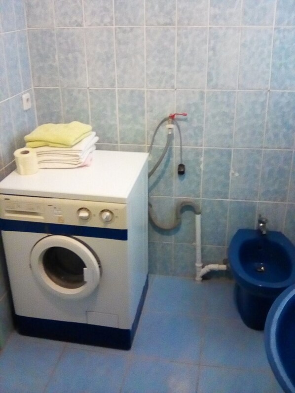 A small laundry area with a washing machine, a stack of towels, and a blue urinal. - Apartment in Ždrelac with Balcony, Air condition, WIFI, Washing machine (4834-1) (Ždrelac)