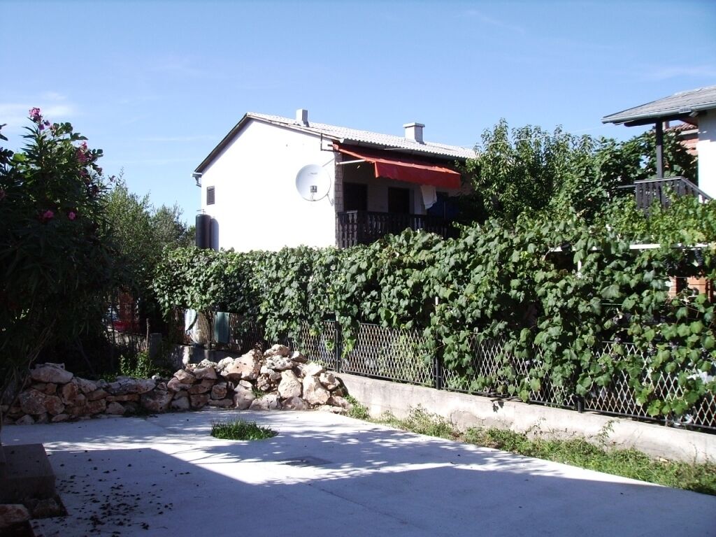 A residential area with a white house, a stone wall, and a metal fence.