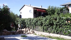 A residential area with a white house, a stone wall, and a metal fence.