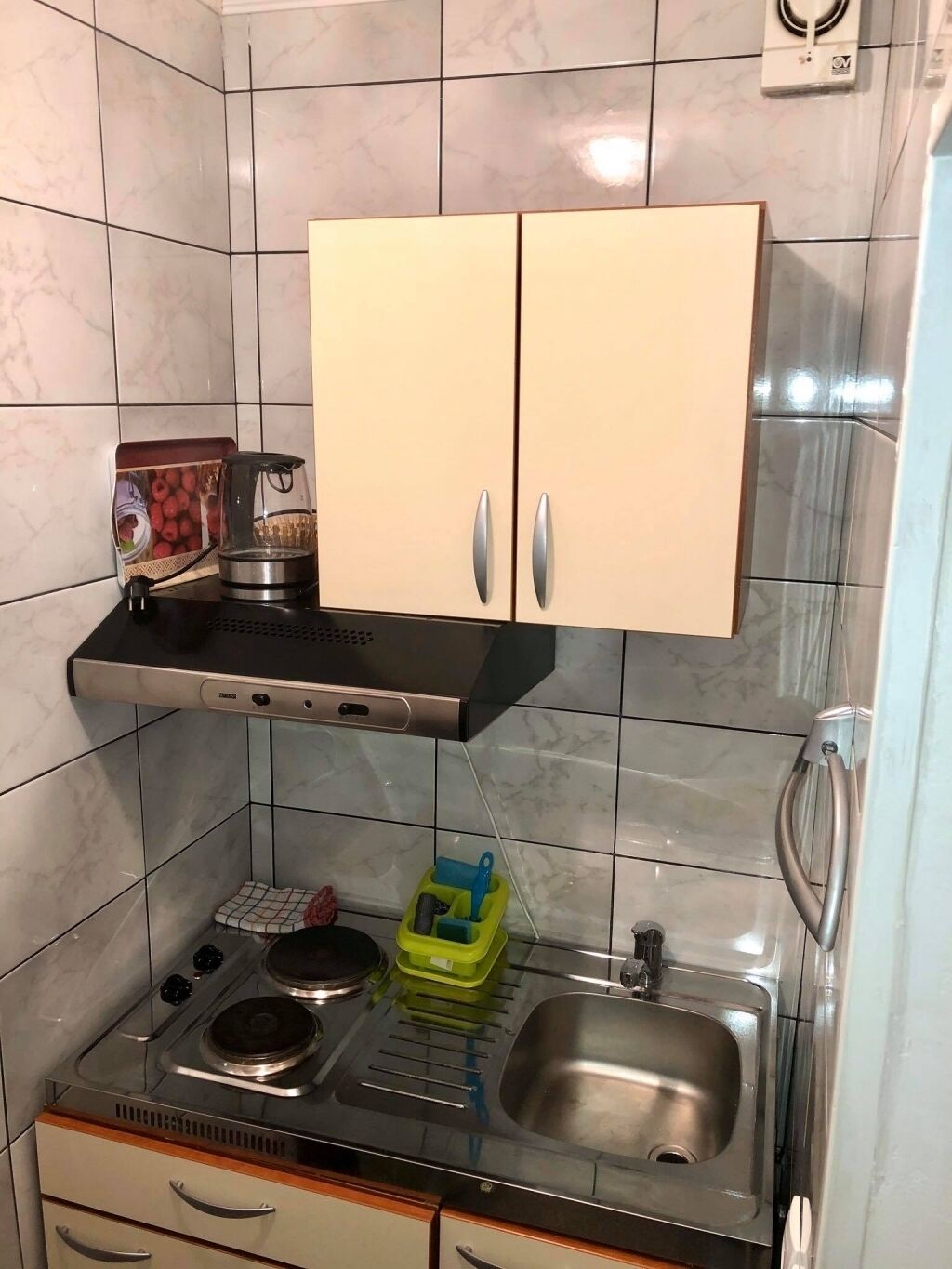 A compact kitchen with a stove, sink, and two cabinets.