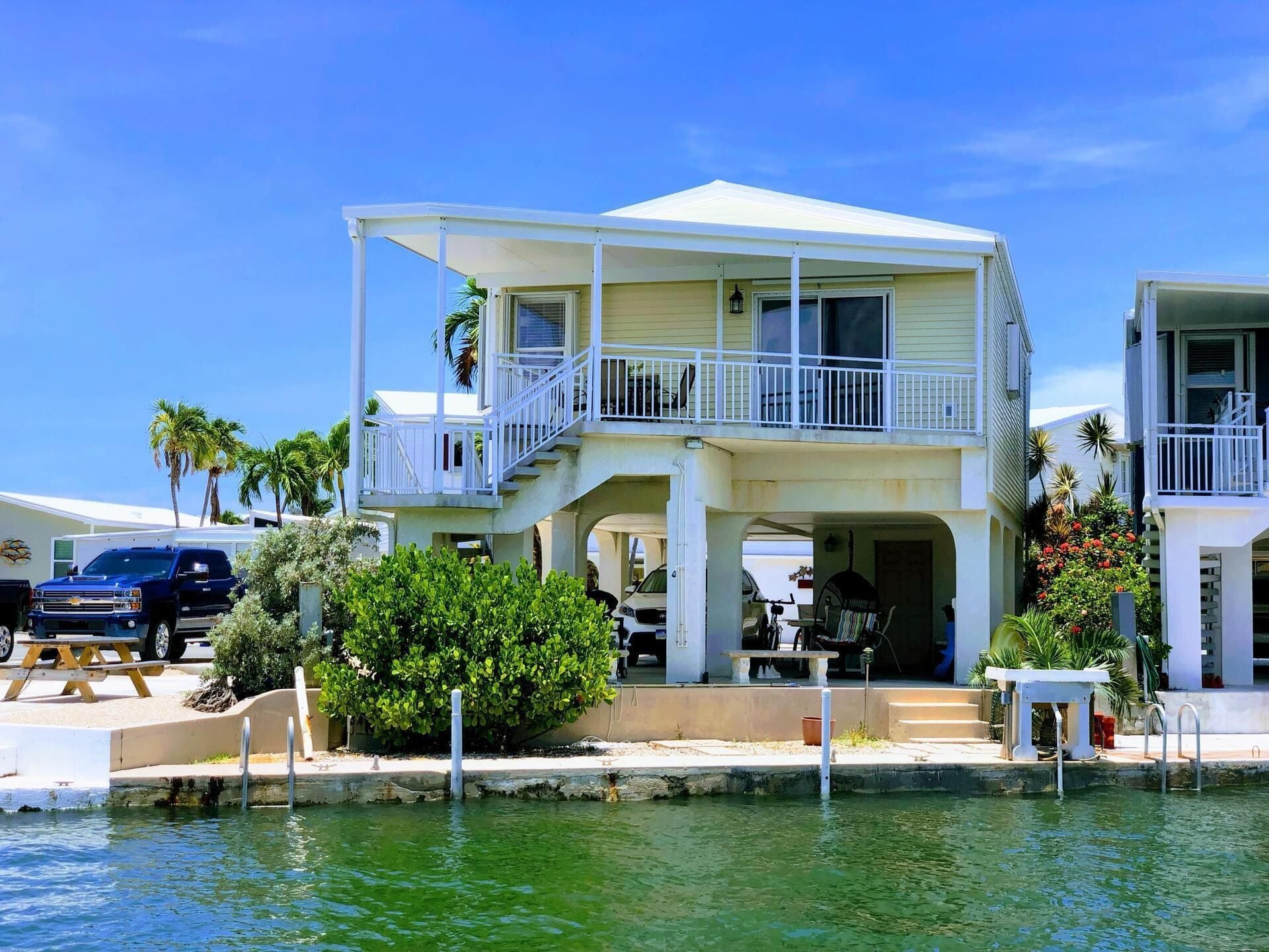 A two-story house with a balcony, a pool, and a dock.