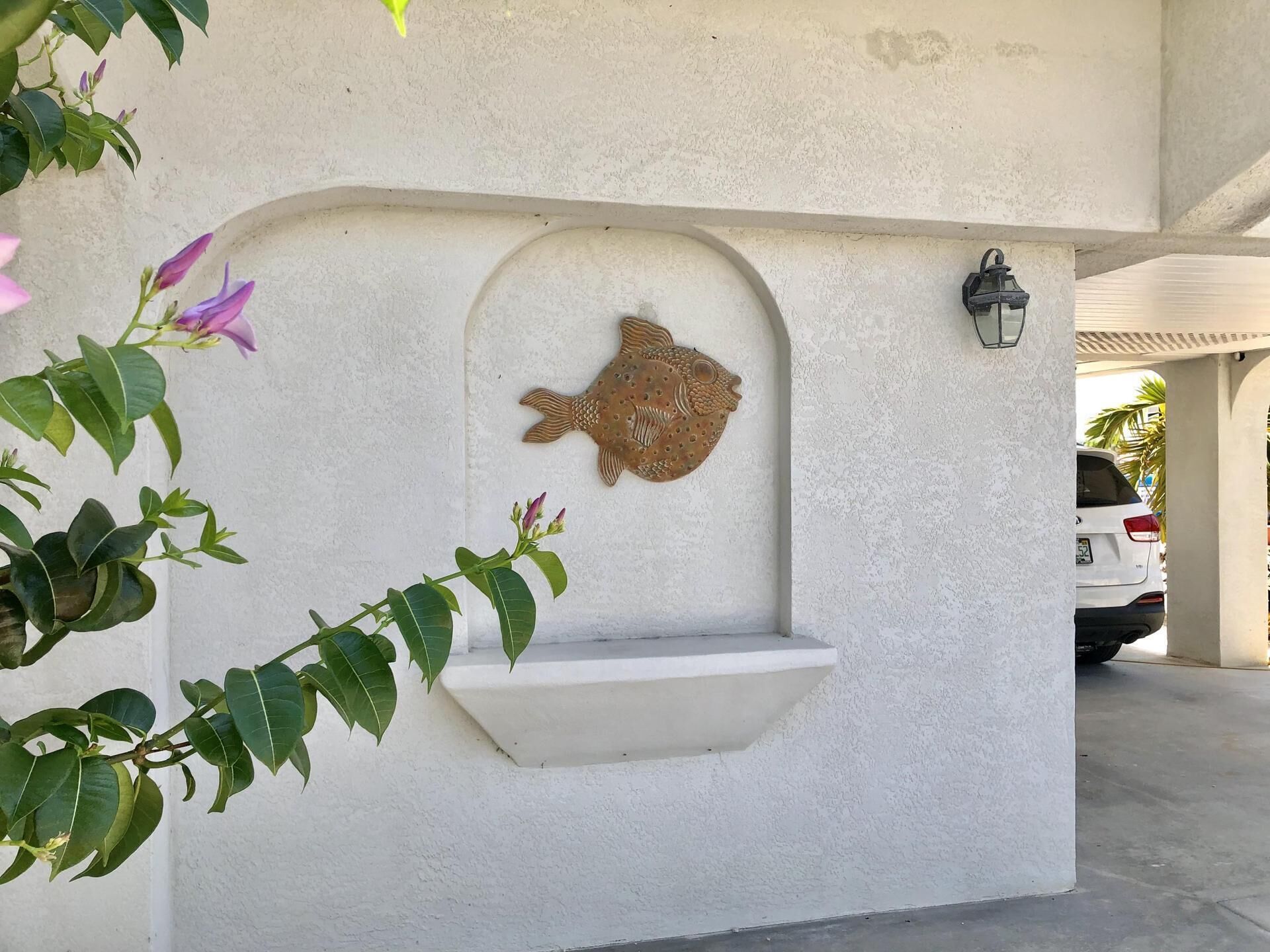 A white wall with a fish-shaped relief and a small shelf.