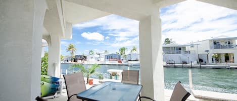 A covered outdoor seating area with a view of a marina and buildings in the background.