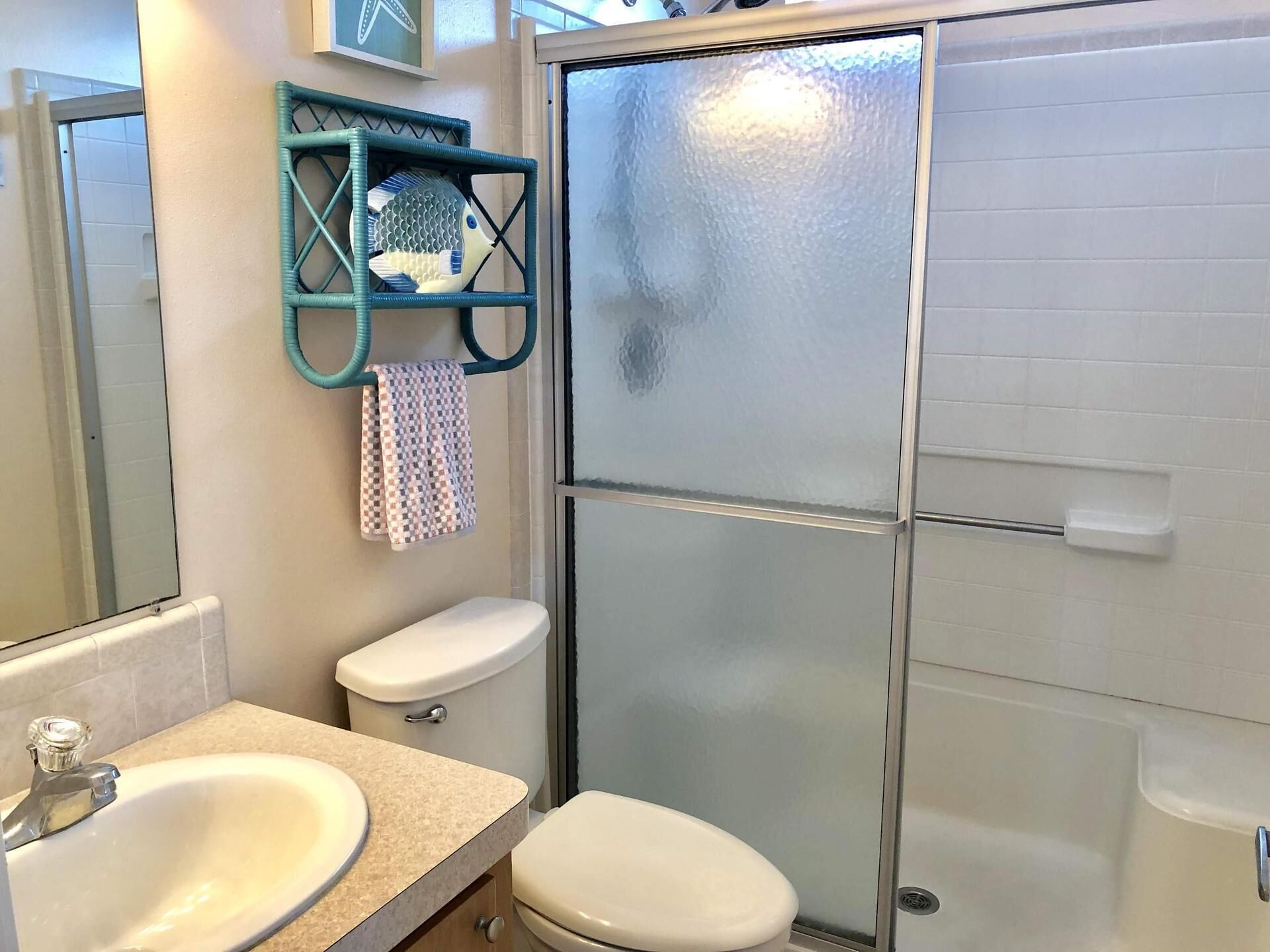 Een badkamer met toilet, wastafel en een douchecabine van glas.