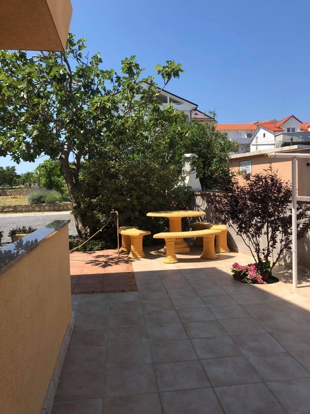 Ein Patio mit Tisch und Stühlen, umgeben von Grünpflanzen und einer Steinmauer.