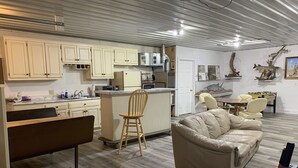 A compact living space with a kitchenette, a dining area, and a seating area with a sofa and chairs. - ARTISTS & ANGLERS INN - game room - home of Madison Lake Paddlefish!! (Madison Lake)