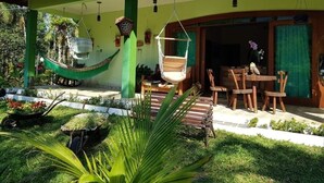 Une maison avec une véranda, un hamac et du mobilier d’extérieur.
