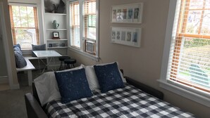 A bedroom with a checkered bedspread, two pillows, a desk, and a chair.
