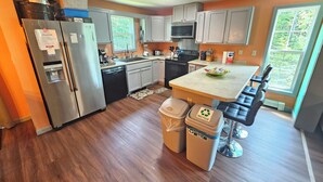 Una cocina moderna con electrodomésticos de acero inoxidable, gabinetes blancos y una isla central con asientos.