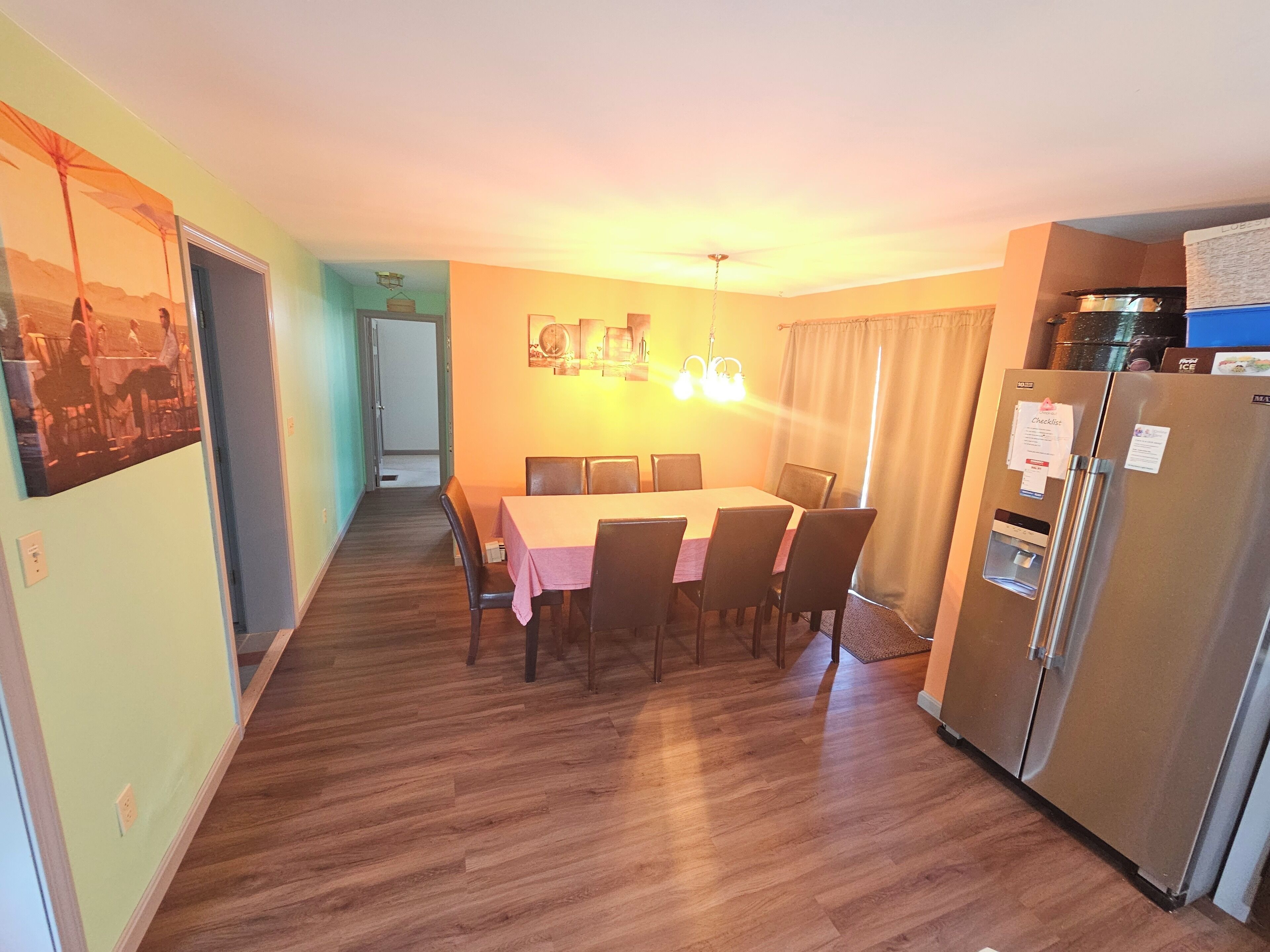 A dining area with a table and chairs, a refrigerator, and a kitchen counter.