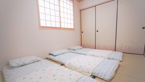 A room with three beds, a large window, and a wardrobe with floral designs. - SC1 Kaikanoyado (Osaka)