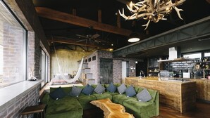 A modern interior with a green sofa set, a wooden coffee table, and a kitchen area with a bar. - Coton (Kanonji)