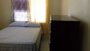 Ein Schlafzimmer mit einem Bett, einem Schminktisch und einem Fenster mit Vorhängen.