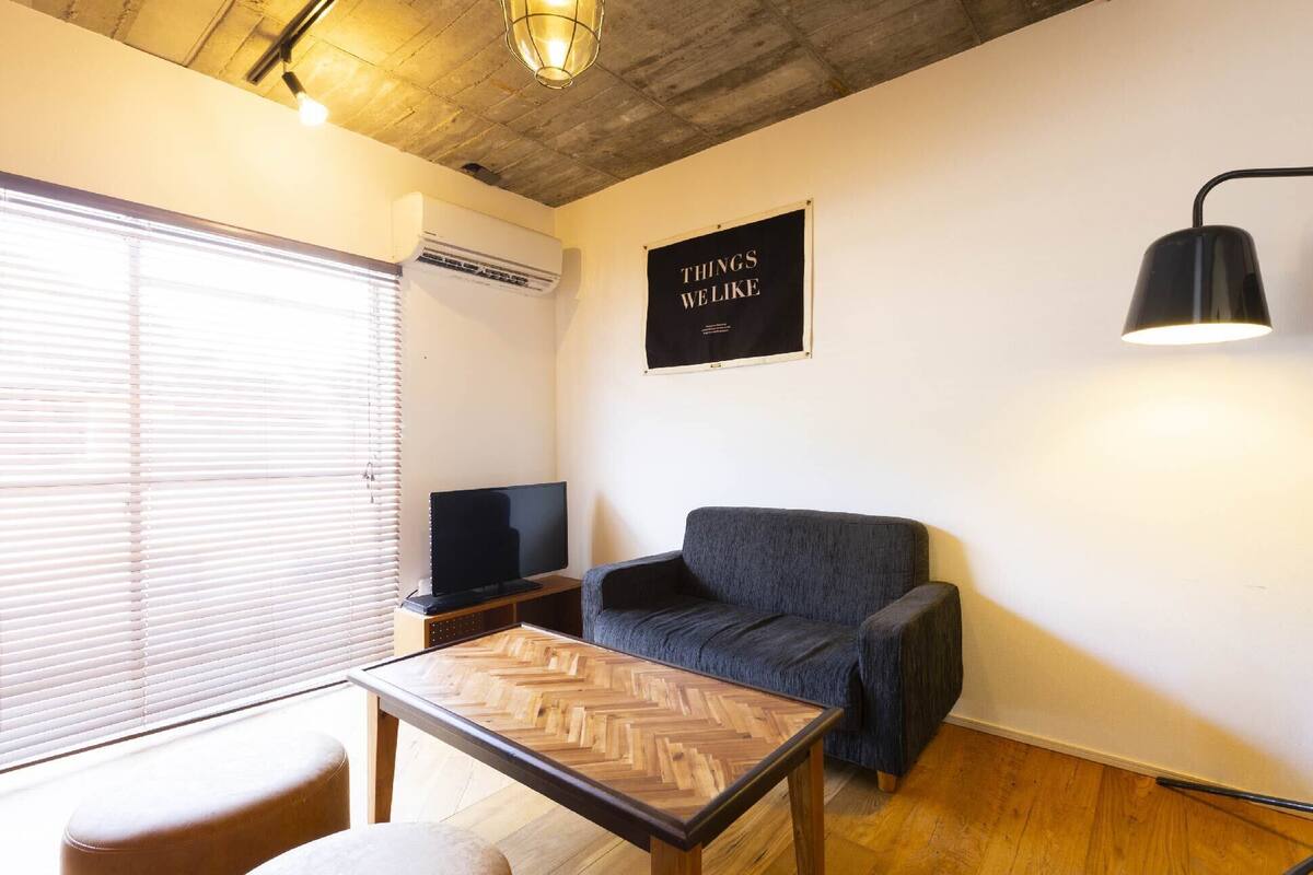 A living room with a television, a sofa, a coffee table, and a wall-mounted lamp.