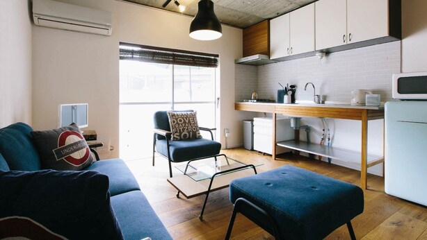 A compact living space with a kitchenette, a sofa, a chair, and a dining table.