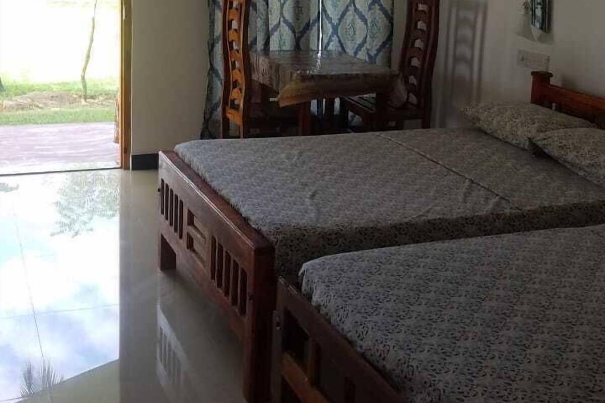 A bedroom with two wooden beds, a dining table, and chairs.