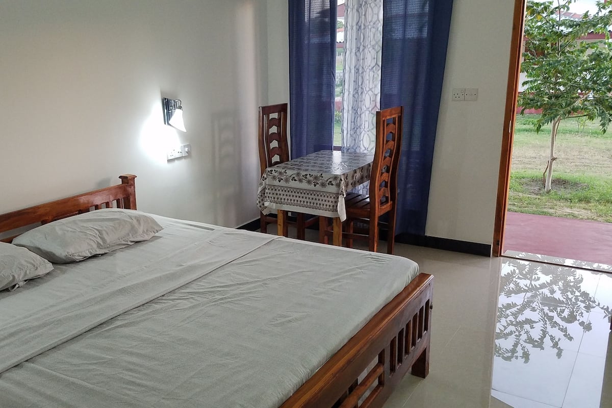 A bedroom with a bed, a table, and chairs.