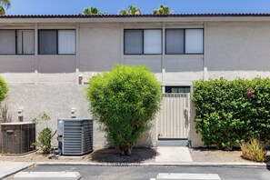 Un bâtiment à la façade blanche, doté d’une entrée fermée par un portail et de deux unités de climatisation à l’avant.