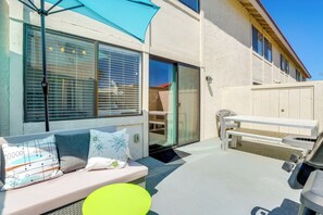 Une terrasse extérieure avec un banc, une table et un parasol.