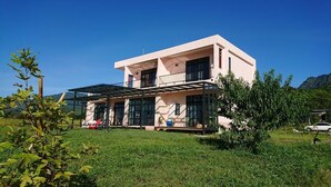 A two-story house with a flat roof, large windows, and a covered patio area. - Moshang Caoxun (Changbin)