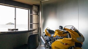 A modern room with a large window, a yellow motorcycle, and a bar area. - Tsushima (Mitoyo)