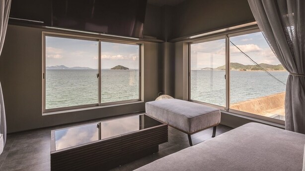 A modern room with large windows offering a view of the sea and distant mountains. - Tsushima (Mitoyo)