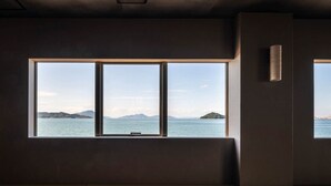 A room with a large window offering a view of the sea and distant islands. - Tsushima (Mitoyo)
