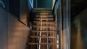 A modern staircase with glass railings and wooden steps. - Tsushima (Mitoyo)