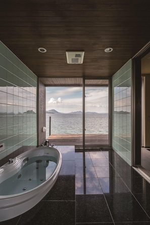 A bathroom with a large bathtub, a view of the sea, and a wooden ceiling. - Tsushima (Mitoyo)