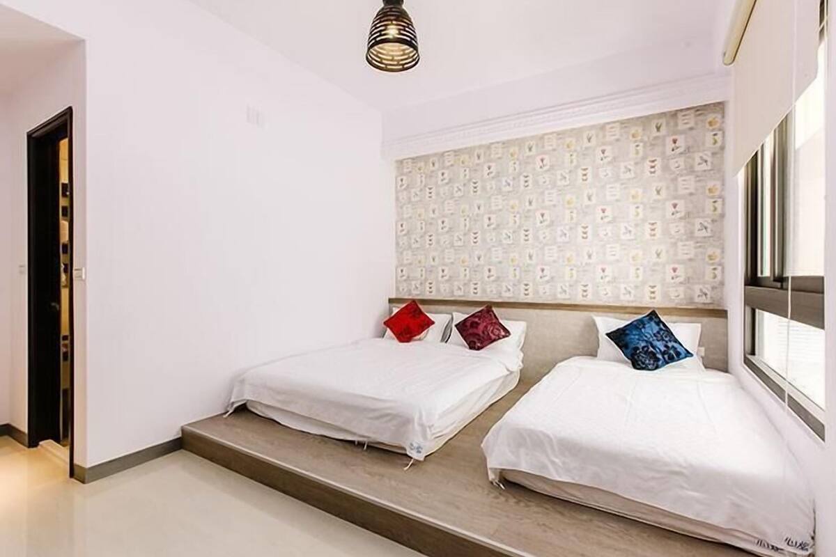 Habitación de hotel con dos camas, un cabecero estampado y una lámpara moderna.