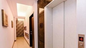 Un pasillo con suelo de mármol, pared de piedra y una puerta que da a una habitación. Se observa el número 4 en la pared, indicando el número de la habitación.