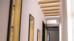 Un pasillo con listones de madera en el techo, espejos enmarcados en las paredes y un suelo brillante.