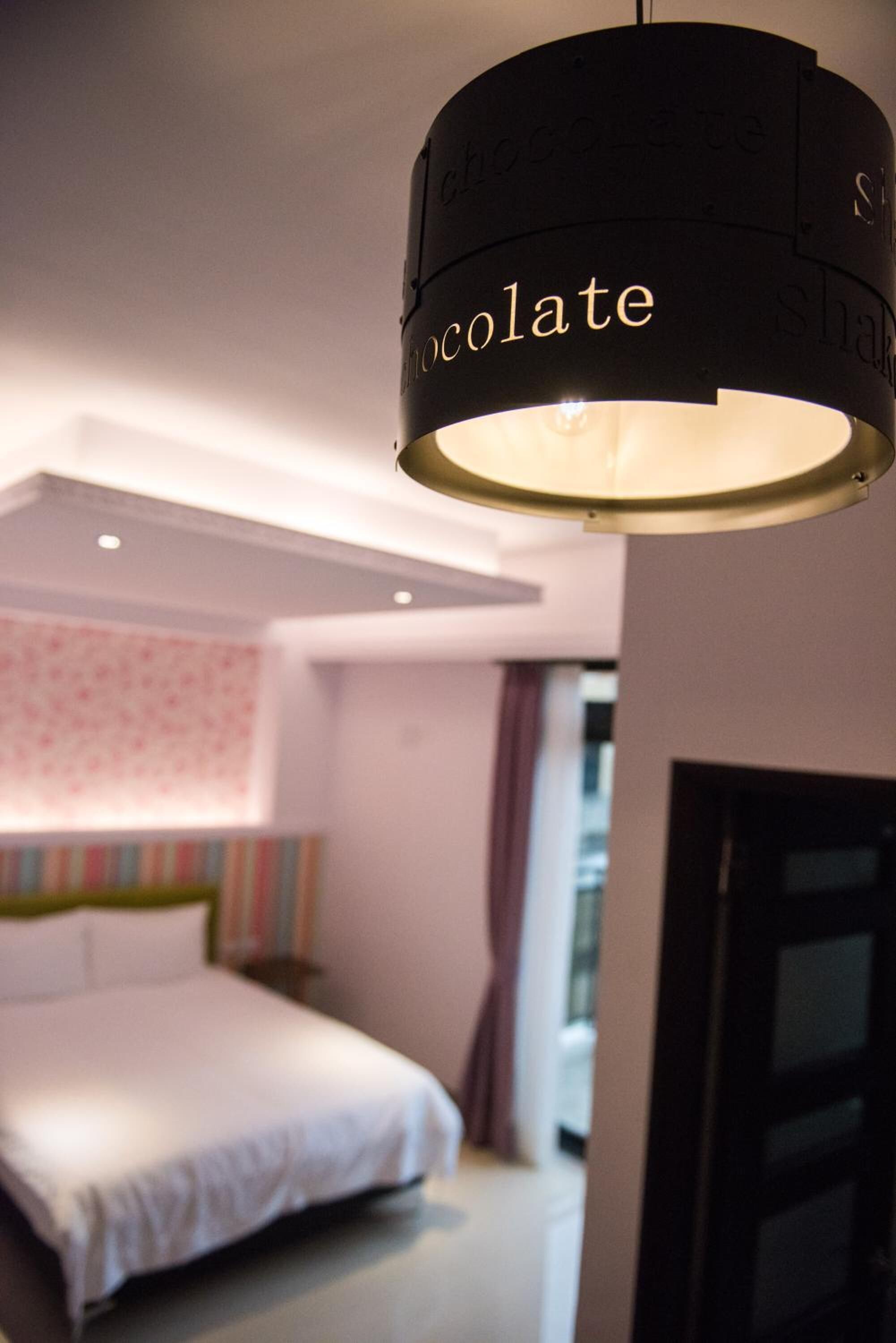 A modern bedroom with a bed, a wall-mounted light fixture, and a window.