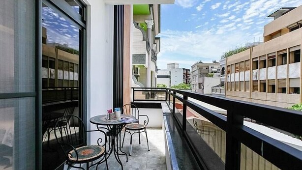Un balcón con mesa y sillas, con vista a una zona residencial con edificios.